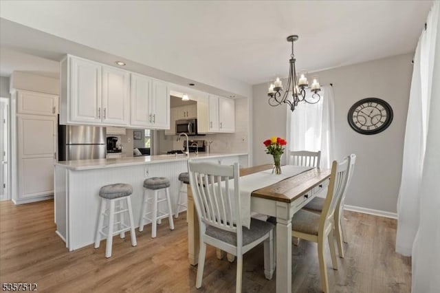 dining area featuring a chandelier, light wood-style flooring, and baseboards