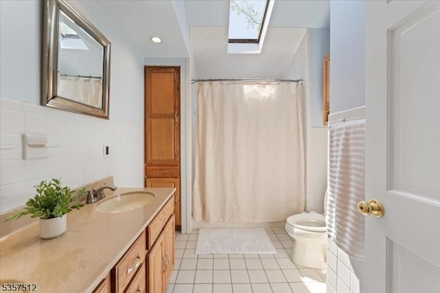 full bathroom with tile patterned floors, vanity, toilet, curtained shower, and a wainscoted wall