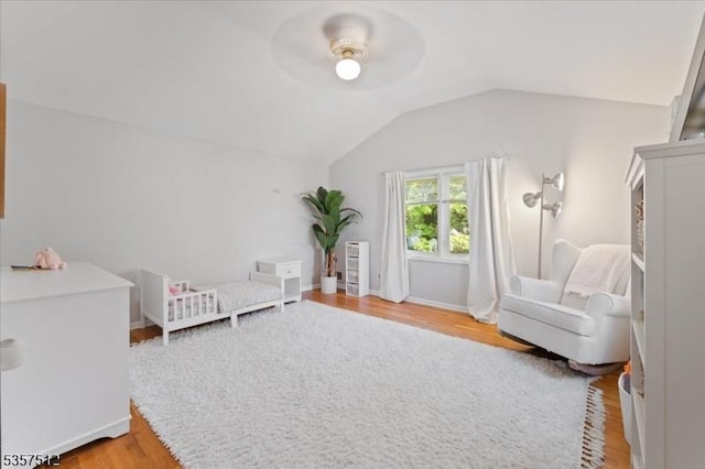 bedroom with vaulted ceiling, light wood-type flooring, a ceiling fan, and baseboards