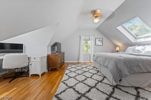 bedroom with a skylight, light wood-style floors, lofted ceiling, ceiling fan, and baseboards
