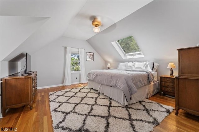 bedroom featuring a skylight, light wood-style floors, lofted ceiling, and ceiling fan