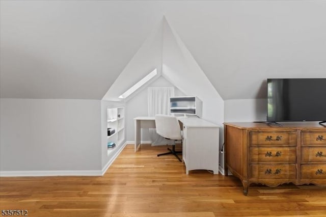home office featuring built in features, lofted ceiling, and light wood-type flooring