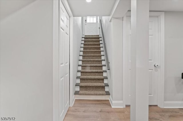 staircase featuring wood finished floors and baseboards