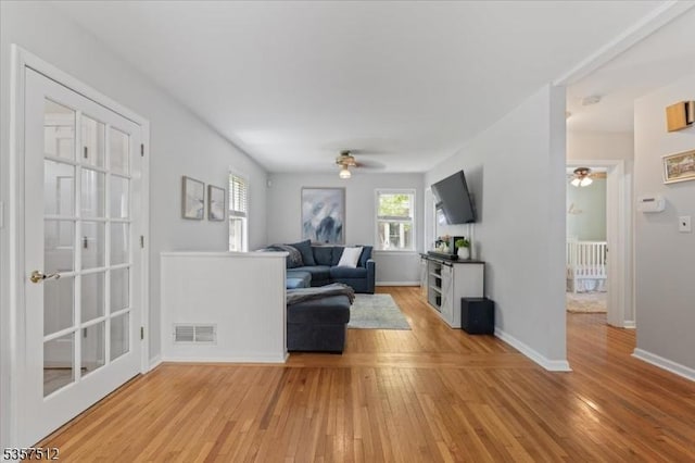 living room featuring ceiling fan, light wood finished floors, and baseboards