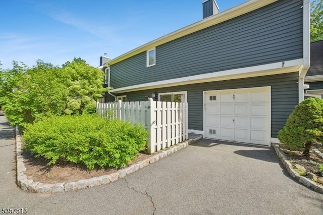 69 Village Dr, Bernards Twp, NJ 07920 - view of side of home featuring a garage, driveway, and a chimney