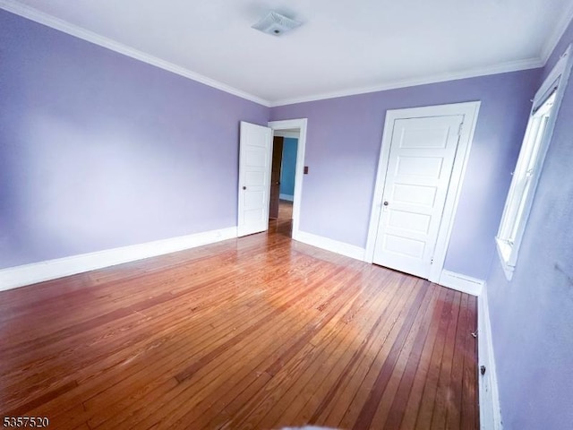 unfurnished bedroom with wood-type flooring, baseboards, and crown molding