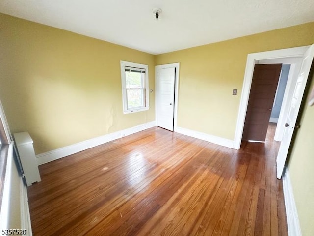 unfurnished room featuring hardwood / wood-style floors and baseboards