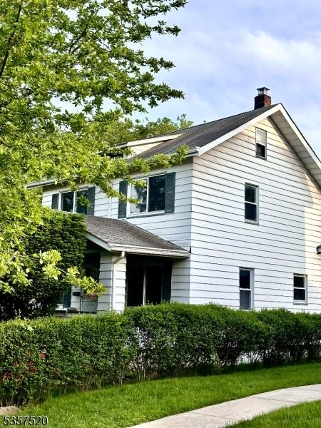 view of side of home featuring a chimney and a shingled roof