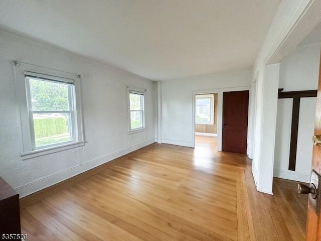 empty room with light wood-style flooring, plenty of natural light, and baseboards