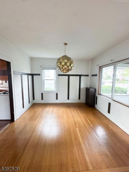 unfurnished dining area featuring light wood finished floors, plenty of natural light, and a chandelier