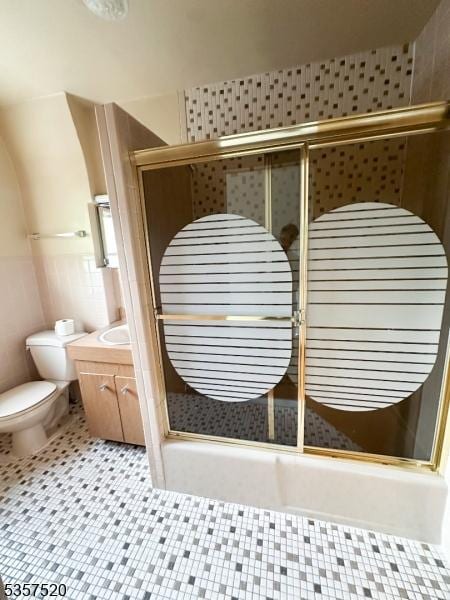 bathroom featuring a stall shower, toilet, vanity, and tile walls