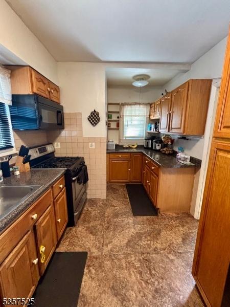 18 Park Dr N, West Orange Twp, NJ 07052 - kitchen featuring stainless steel gas range oven, black microwave, a sink, brown cabinetry, and tile walls