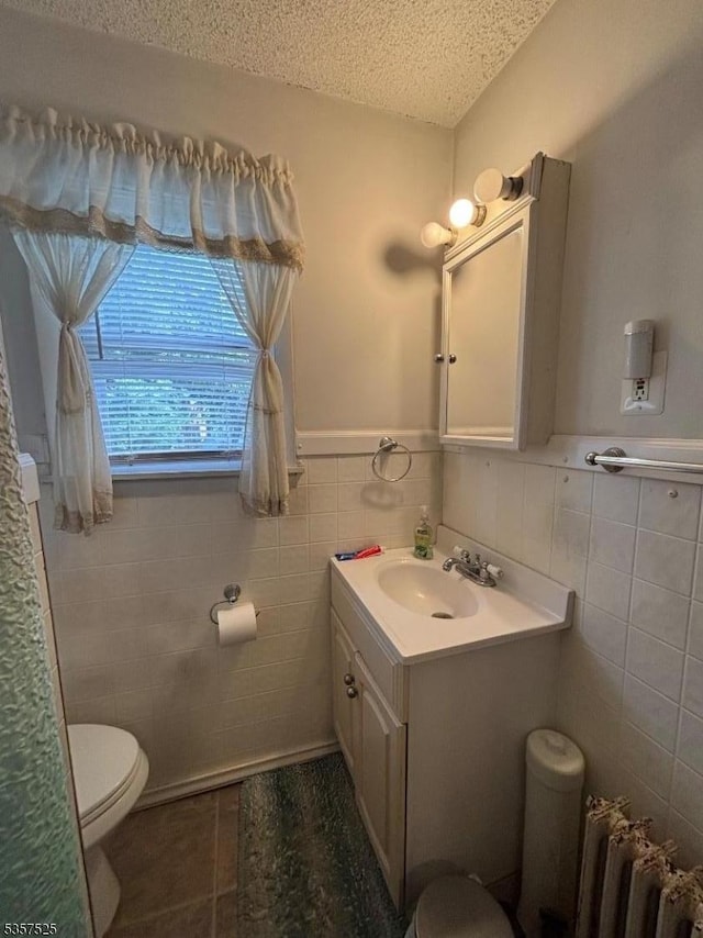 18 Park Dr N, West Orange Twp, NJ 07052 - bathroom featuring tile walls, a textured ceiling, toilet, radiator heating unit, and vanity