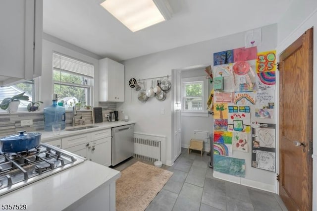 kitchen with a sink, appliances with stainless steel finishes, light countertops, decorative backsplash, and light tile patterned floors