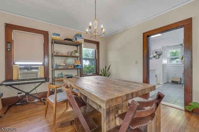 dining room featuring a chandelier, hardwood / wood-style floors, healthy amount of natural light, cooling unit, and crown molding