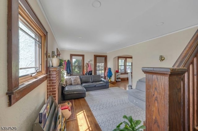 living room featuring arched walkways, ornamental molding, wood finished floors, and stairway