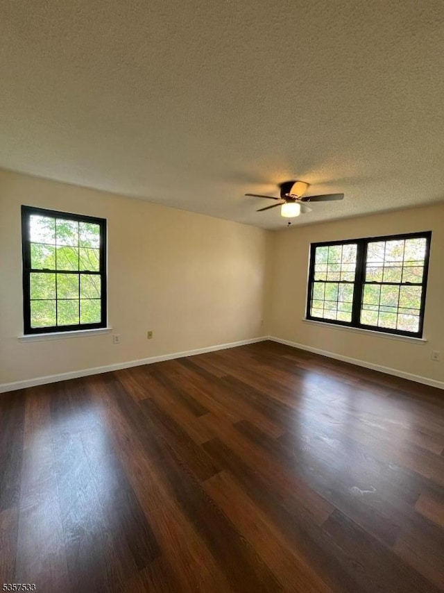 unfurnished room with dark wood-style flooring, baseboards, ceiling fan, and a textured ceiling