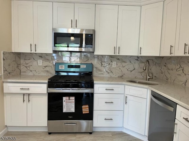 kitchen with stainless steel appliances, a sink, and white cabinets