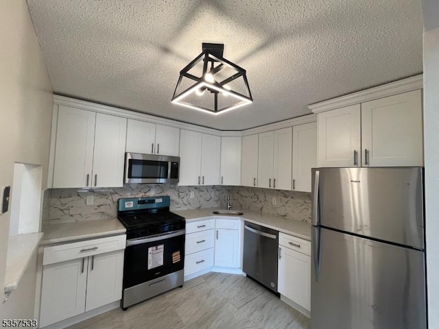 kitchen featuring appliances with stainless steel finishes, a sink, white cabinetry, light countertops, and a textured ceiling