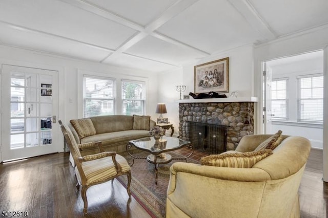 living area with wood finished floors, a stone fireplace, coffered ceiling, and beamed ceiling