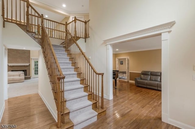102 Independence Dr, Bernards Twp, NJ 07920 - staircase featuring wood finished floors, baseboards, a large fireplace, a high ceiling, and ornamental molding