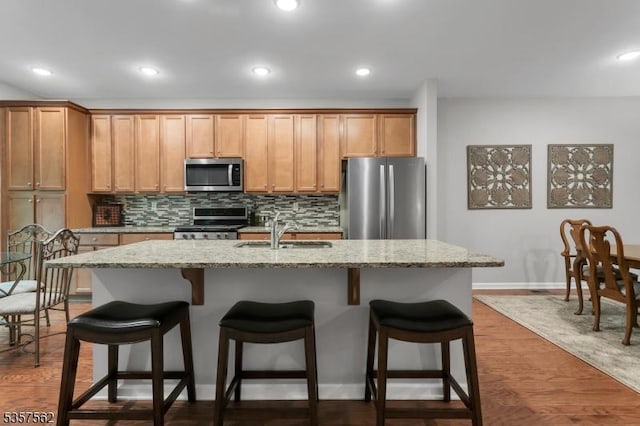 18 Brompton Pl, Randolph Twp, NJ 07869 - kitchen featuring stainless steel appliances, a sink, backsplash, light stone counters, and a breakfast bar