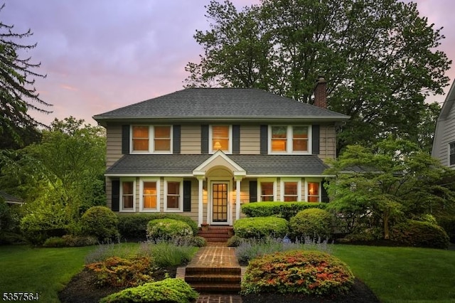 view of front of home featuring a chimney and a lawn