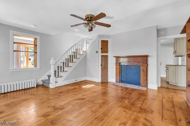392 Pittstown Rd, Franklin Twp, NJ 08867 - unfurnished living room featuring radiator, stairway, a ceiling fan, a fireplace with raised hearth, and light wood-type flooring