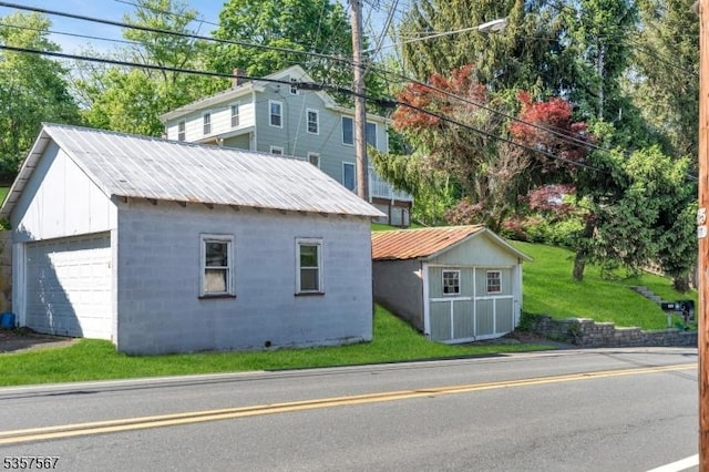 392 Pittstown Rd, Franklin Twp, NJ 08867 - view of side of home featuring an outdoor structure, a garage, concrete block siding, metal roof, and a lawn