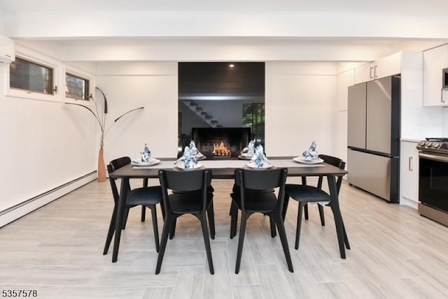 203 Stanhope Rd, Sparta Twp, NJ 07871 - dining area featuring light wood finished floors, a baseboard radiator, and a warm lit fireplace