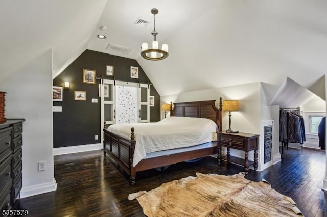 bedroom featuring baseboards, wood finished floors, lofted ceiling, and a walk in closet