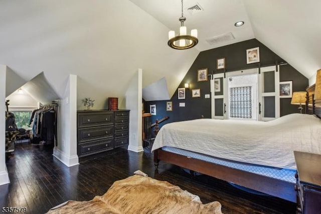bedroom with vaulted ceiling, wood-type flooring, baseboards, a walk in closet, and a chandelier