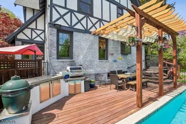 deck with exterior kitchen, a pergola, an outdoor pool, and a grill