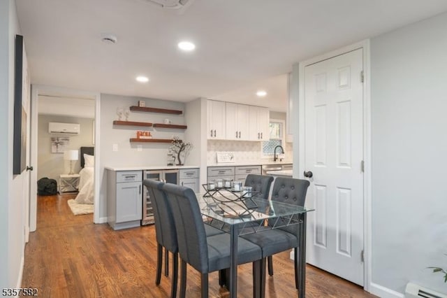 dining area featuring a baseboard heating unit, bar, wood finished floors, beverage cooler, and a wall mounted AC