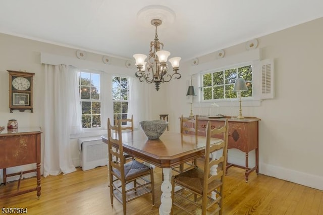 dining area featuring a chandelier, light wood finished floors, and baseboards