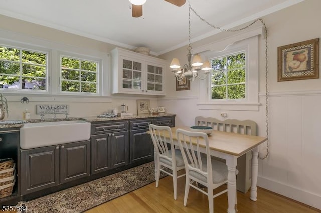 dining area featuring crown molding, healthy amount of natural light, a chandelier, light wood-style flooring, and a decorative wall