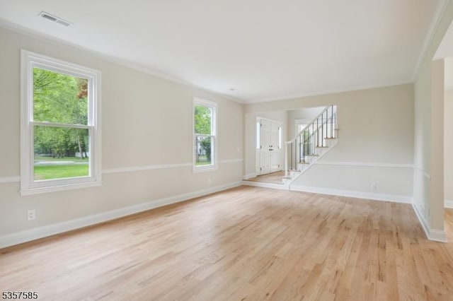 spare room with light wood-type flooring, baseboards, stairs, and crown molding