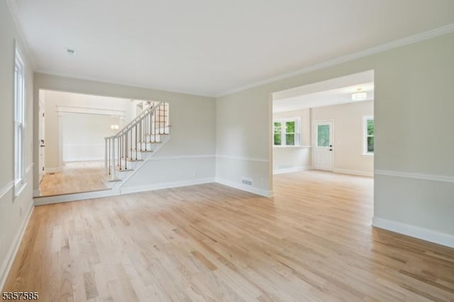 spare room with stairs, light wood-type flooring, ornamental molding, and baseboards