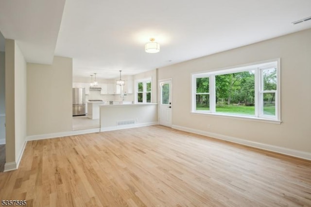 unfurnished living room with light wood-style flooring and baseboards
