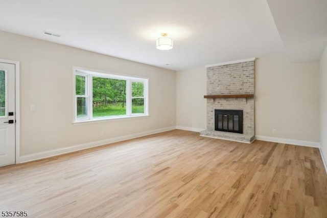 unfurnished living room with light wood-type flooring, baseboards, and a fireplace