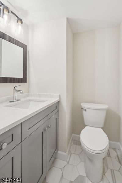 bathroom featuring toilet, vanity, and baseboards