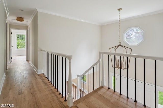 hall featuring an upstairs landing, wood finished floors, crown molding, and a chandelier