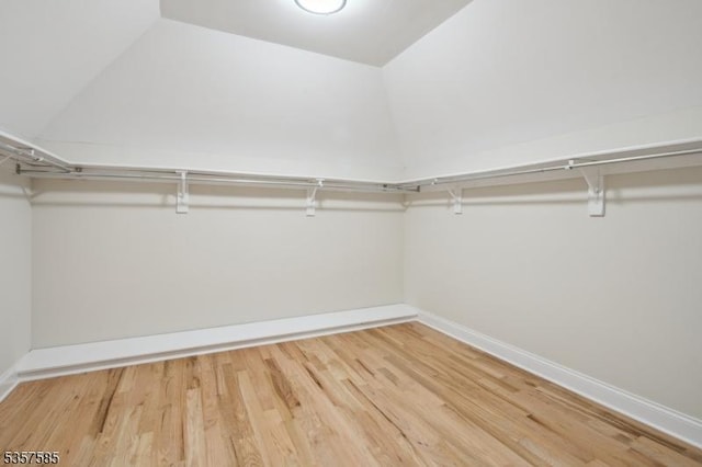 walk in closet featuring wood finished floors and lofted ceiling