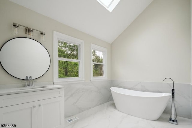 bathroom with tile walls, marble tiled floors, a wainscoted wall, vanity, and a freestanding bath