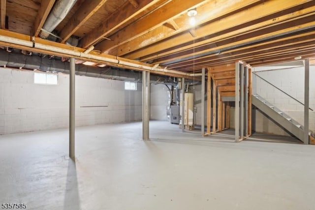 basement featuring gas water heater, stairway, and heating unit