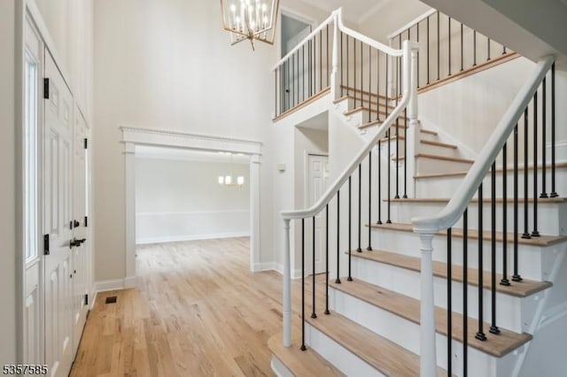foyer featuring a chandelier, a towering ceiling, wood finished floors, stairs, and baseboards