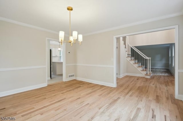 spare room featuring a chandelier, crown molding, light wood-style floors, stairway, and baseboards