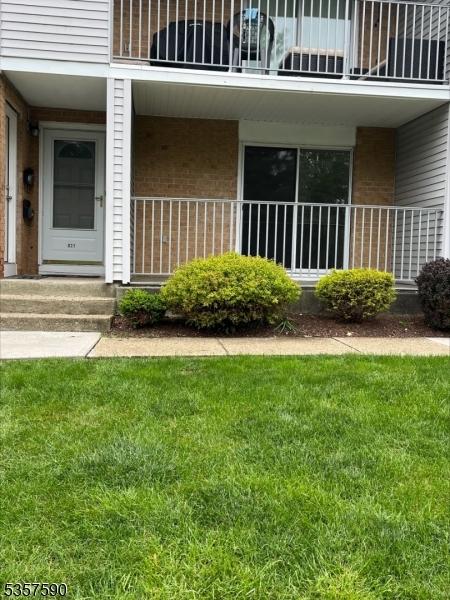 doorway to property with brick siding, a balcony, and a lawn