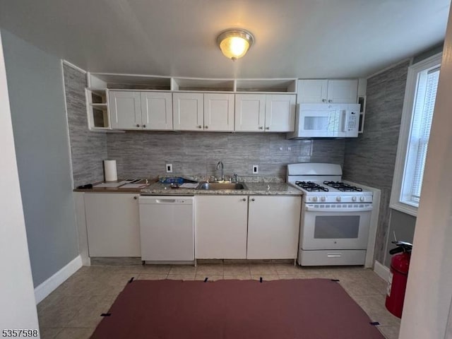 kitchen with white appliances, a sink, plenty of natural light, and white cabinetry