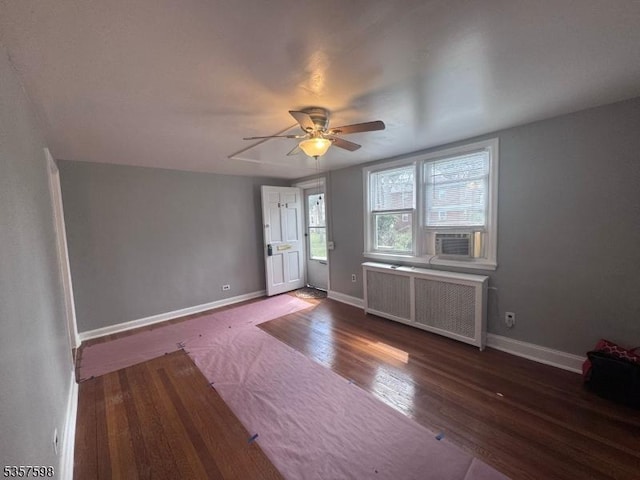 unfurnished living room featuring radiator heating unit, ceiling fan, wood finished floors, baseboards, and cooling unit